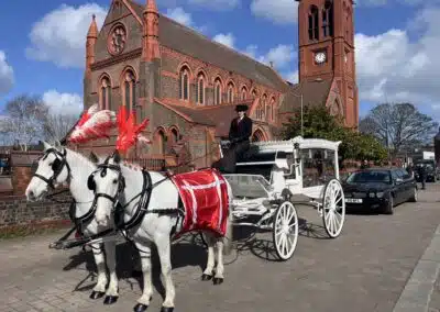 White horse drawn funeral carriage outside church in St Helens by Walkers Funeral Service